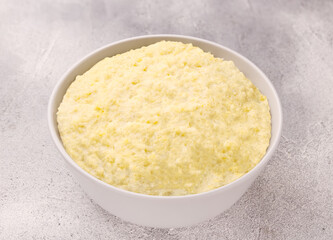 Vegetarian breakfast: millet porridge in a white plate on a gray background
