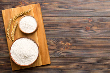 Flat lay of Wheat flour in wooden bowl with wheat spikelets on colored background. world wheat crisis