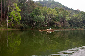 Obraz premium Thai rower waterman rowing bamboo rafts in Pang Ung lake for service travelers people travel visit Pang Oung or Switzerland of Thai at Ban Rak Thai on February 28, 2020 in Mae Hong Son, Thailand
