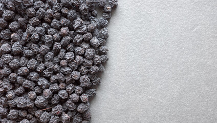 Close up photo of organic dried aronia berries on a dark slate background, selective focus.