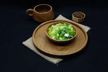 Chopped spring onions on wooden bowl isolated on a white background