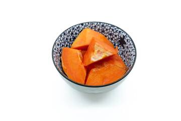 Freshly cut orange papaya arranged neatly in a ceramic bowl isolated on a white background