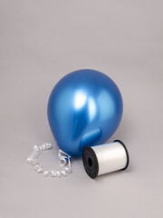 Blue balloon with white ribbon on grey background and ribbon spool, space for text