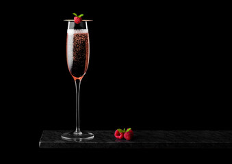 Elegant glass of pink rose champagne with raspberry on stick with fresh berries and mint leaf on black marble board on black background.Space for text