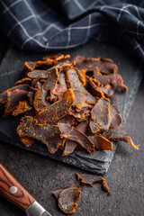 Beef jerky. Dried spiced meat on black table.