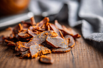 Beef jerky. Dried spiced meat on wooden table.