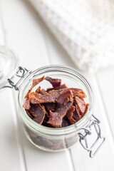 Beef jerky. Dried spiced meat in jar on white table.