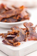 Beef jerky. Dried spiced meat on white table.