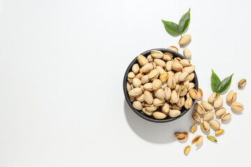 Pistachios in the shell with leaves, on a light background.