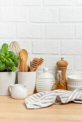 Kitchen utensils, basil plant and linen napkin creating cozy atmosphere on table