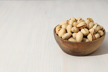 Pistachios in a wooden plate, on a light background.