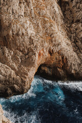 Sardinian sea and cliffs. Turquoise water entering cave in the rocks.