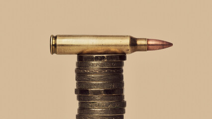UK Defense Spending- still life of bullet cartridge on stack of British Pound coins
