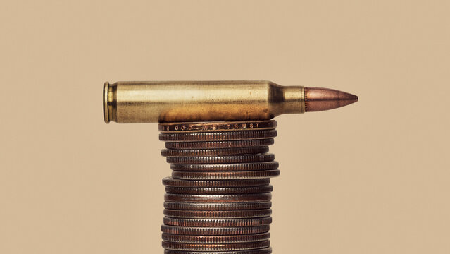 US Defense Spending - still life of bullet cartridge on stack of US money coins
