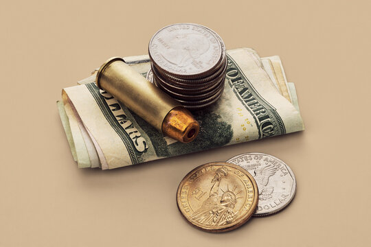 US Defense Spending - still life of bullet cartridge and quarters on stack of US money bills
