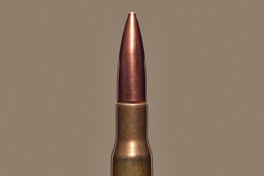Close up studio shot .50 BMG bullet cartridge on brown background

