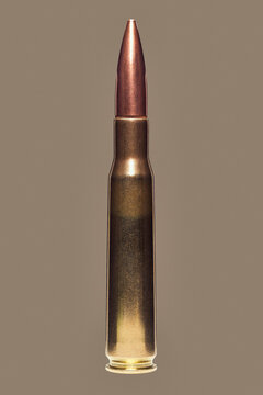 Close up studio shot of .50 BMG bullet on brown background
