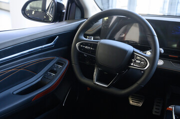 Modern car interior with black steering wheel, digital instrument panel