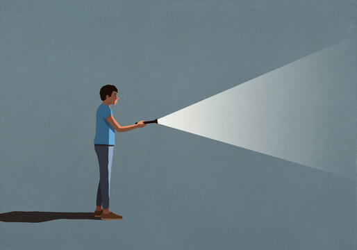 Man holding bright flashlight in dark
