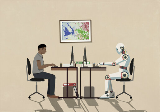 Man and humanoid robot working face to face at computers
