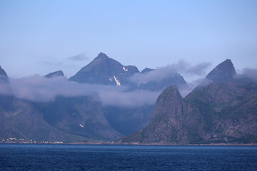 Fantastic mountain landscape on the coast of the island of Moskenes emerges from the morning mist, Lofoten, Norway 