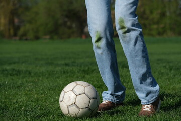 A young player standing on a vibrant green soccer field, ready to kick a classic soccer ball. Grass...