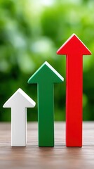 Three upward pointing arrows in white green and red symbolize growth progress success and improvement on a wooden surface with vibrant green blurred background