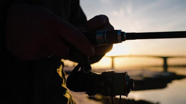 Winter fishing capturing golden sunrise moment, standing on frozen lake with fishing rod, sunlight reflecting on reel and fishing line during peaceful morning activity