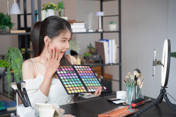 Asian woman influencer beauty blogger live streaming reviews her cosmetics on online platform