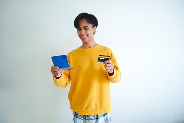 Happy Asian man holding a bank book with a proud smile, showing positive financial expression