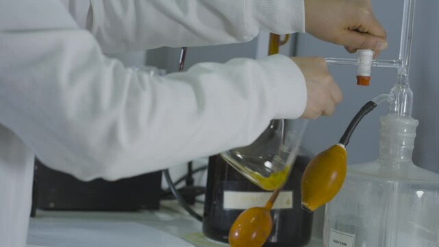 Medium shot of a laboratory scene with a flask and burette containing moving liquids.