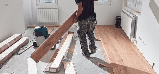 Professional handyman installing laminate flooring in a new apartment.