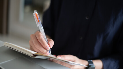 Close-up hand of person writing working document note paper office pen desk planning finance concept