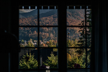 Horizontal window frame view to the chalet, forest and mountains at sunset. Autumn mountain landscape in Zakopane, Poland.