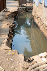 Construction site in Indian, excavated road filled with dirty, stinking water, unsecured damaged...