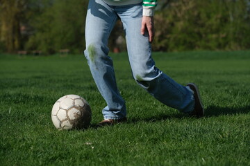 A young player standing on a vibrant green soccer field, ready to kick a classic soccer ball. Grass...