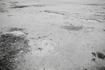 Gray, patchy pavement surface with numerous potholes.