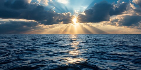 Dramatic ocean sunset with sunbeams breaking through clouds over open sea