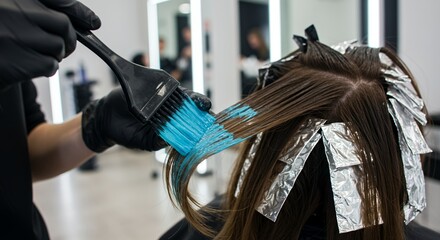Vibrant Turquoise Dye Applied To Long Brown Hair With Foils in Modern Salon With Bright Diffuse Lighting