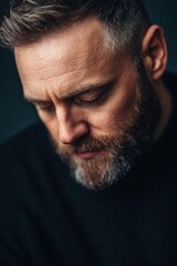 Obraz premium Thoughtful Mature Man with Beard Looking Down - Introspective Portrait.