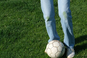 A young player standing on a vibrant green soccer field, ready to kick a classic soccer ball. Grass...