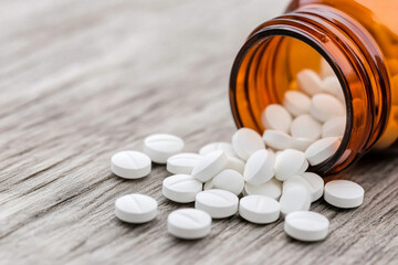 Bottle spills white tablets onto wooden surface creating a chaotic scene of medicine production