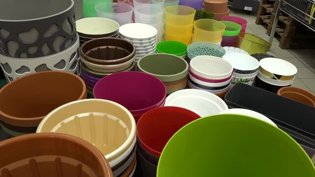 Colorful plastic plant pots and containers arranged on a store display table in various sizes, shapes, and textures, ready for home gardening use.
