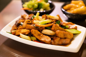 Hakka-style stir-fried squid and pork, Tofu, and scallions on white plate.