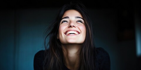 Fototapeta premium Smiling young caucasian woman looking upward in dark setting