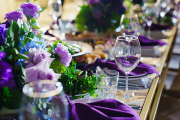 Beautiful festive table setting with flowers and purple napkins.