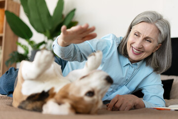 Happy Senior Woman Playing with Beagle Dog on Bed