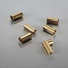 multiple gold-toned cylindrical tubes and one elbow-shaped tube arranged on a reflective surface