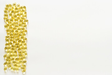 Many transparent orange colored oval shaped capsules scattered on a white background, omega 3 fish oil, lecithin, vitamin D. Border with copy space, mockup