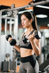 Fototapeta premium woman in a gym with a dumbble and a pair of gloves